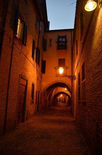 Small arched street at night in Ferrara, Italy
