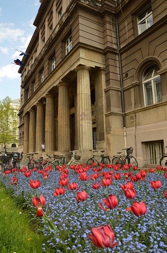Red and purple flowers in front of a columned building in Zagreb, Croatia