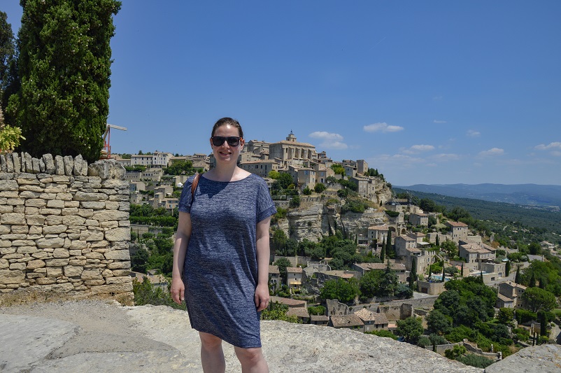Sarah standing in front of a view of Gordes in Provence, France