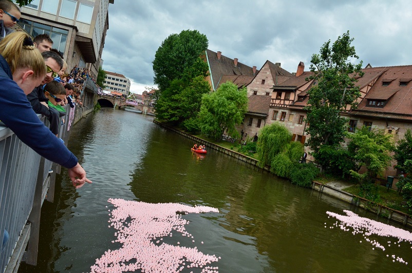People watching the pink ducks race down the river at the Entencup in Nuremberg