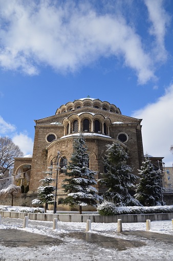 Front view of the Church of St. George Rotunda with snowy trees and blue sky in Sofia