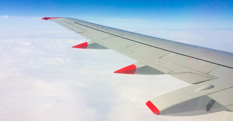 Wing of a plane over clouds and blue sky