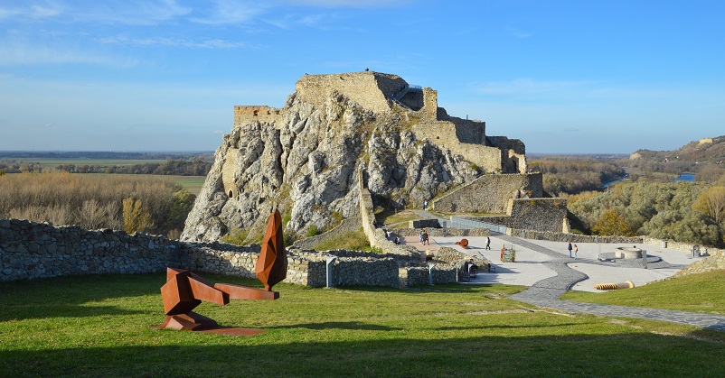 View of castle ruins with path leading to them and a red sculpture at Devin Castle Bratislava