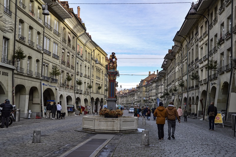People walking down a cobblestone street in the Old Town of Bern, Switzerland