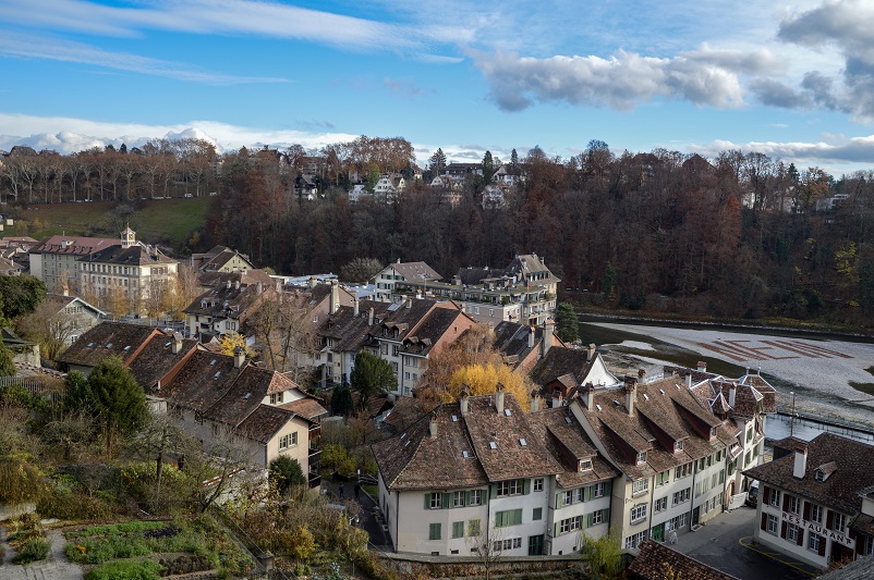 View of old houses and a white sign on a river that says “nein” from the Münsterplattform in Bern, Switzerland