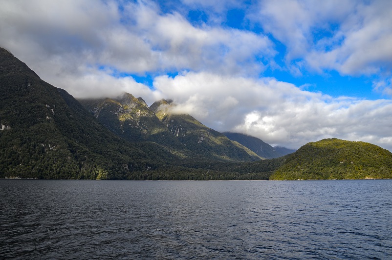 Water and mountains and clouds in the distance on Lake Manapouri in New Zealand