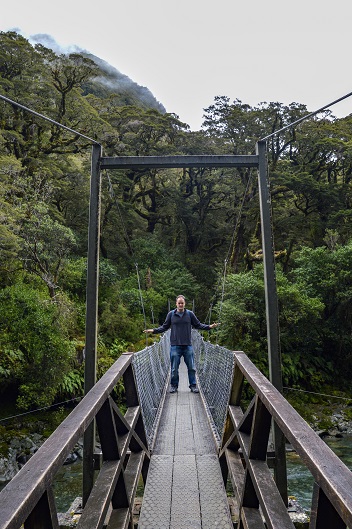 Man on narrow wooden bridge on the Lake Marian Track, South Island, New Zealand