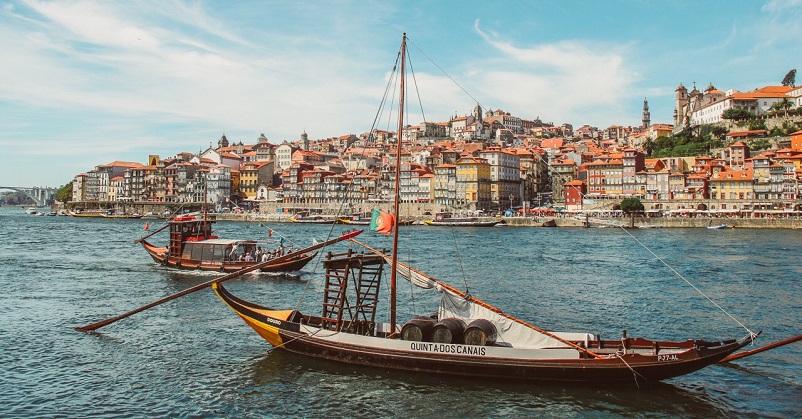 Two boats in the river in front of view of buildings in Porto, Portugal