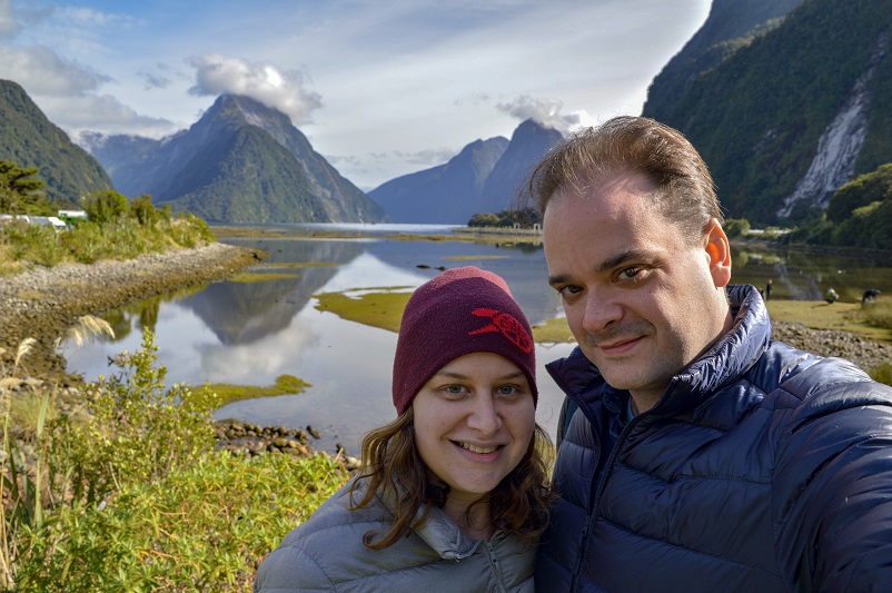 Woman and man in front of mountains and water at Milford Sound
