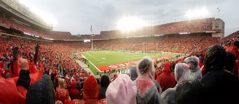 Thousands of people, most of whom are in red ponchos, at a football game at Ohio State University