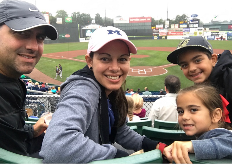 Happy family of four attending a minor league baseball game in Portland, Maine