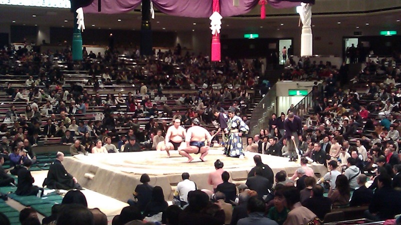 Two sumo wrestlers facing off in front of a crowd of spectators in Tokyo, Japan
