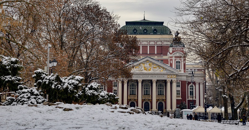 Red National Theater building in snowy park in Sofia, Bulgaria