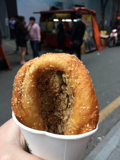 Close-up of a hand holding ssiat hotteok in a white cup in Busan, South Korea