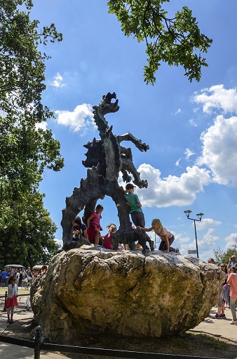 Kids climbing all over a sculpture of a dragon in Krakow