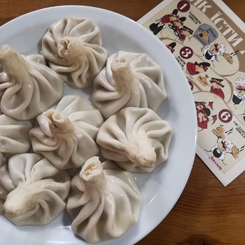 Plate of eight Chinkhali soup dumplings plus instructions for how to eat them in Lviv