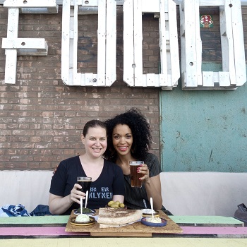 Two women holding beers under a sign that says FOOD at Fenix Food Factory in Rotterdam