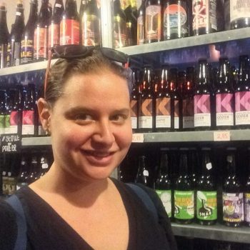 Sarah smiling in front of a shelf of beers in the Netherlands