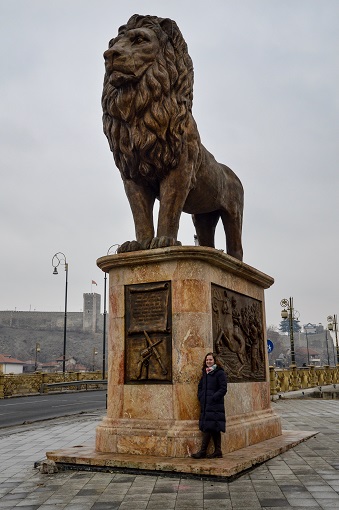 Sarah standing in front of an enormous lion statue in Skopje