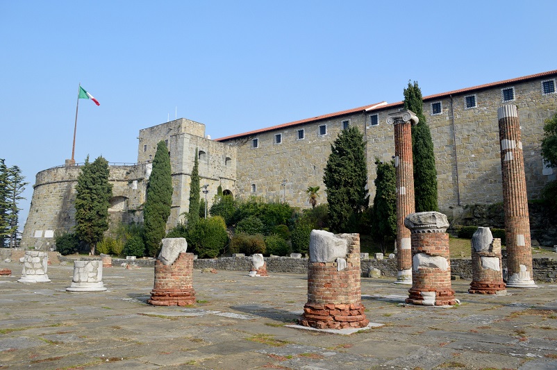 Old brick pillars in front of a castle flying the Italian flag, Trieste