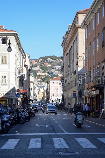 Busy street with houses built on hills in the distance, Trieste