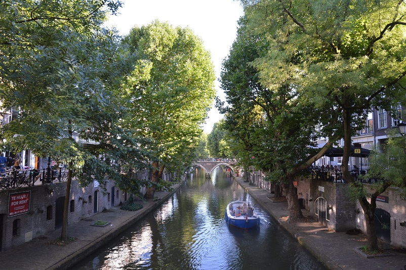 Small boat going down a tree-lined canal in Utrecht, the Netherlands