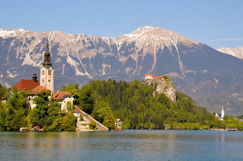 A lake with a castle on an island in front of mountains; Lake Bled, Slovenia