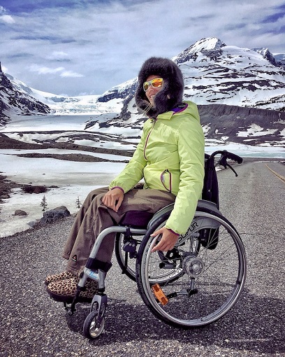 Melanie in her wheelchair in front of snowy mountains in Banff National Park, Canada