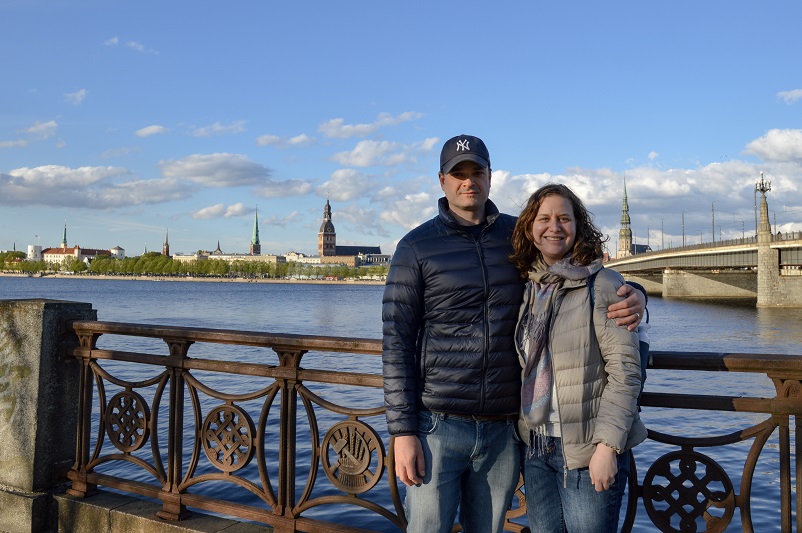 Justin and Sarah standing in front of the Daugava River and Akmens Bridge in Riga