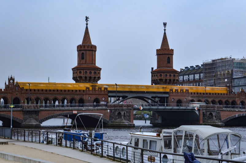 Yellow train going across a bridge with spires in Berlin