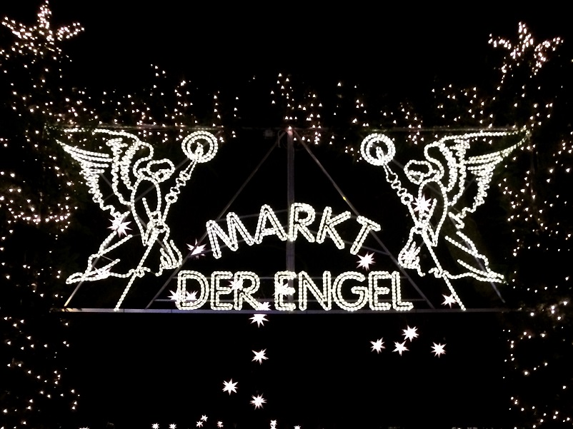 Lit up sign saying "Markt der Engel" with two angels in Cologne