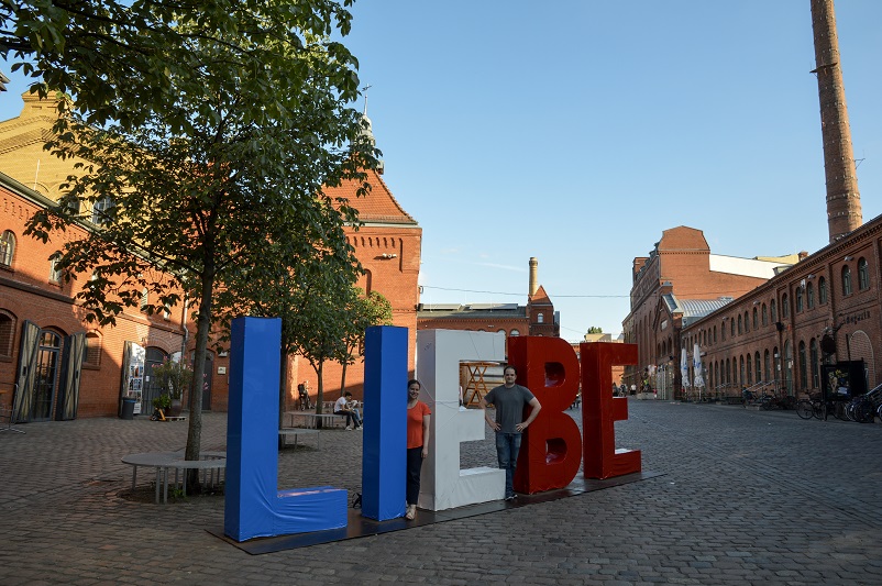 Sarah and Justin standing in the middle of a sign that says "LIEBE" in Berlin