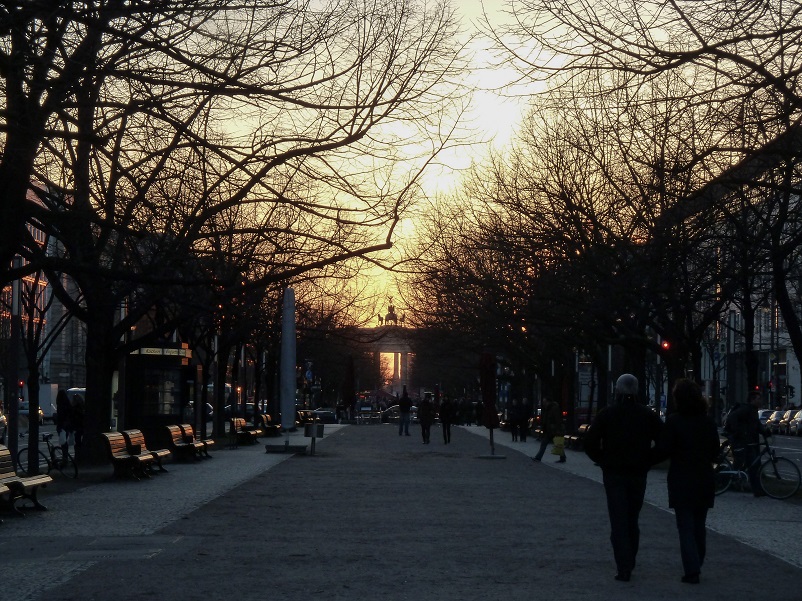 Couple walking down Unter den Linden towards the Brandenburg Gate at sunset in Berlin