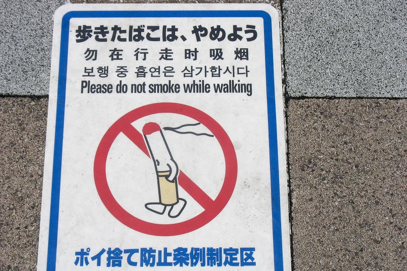 Sign on the ground that says "no smoking while walking"