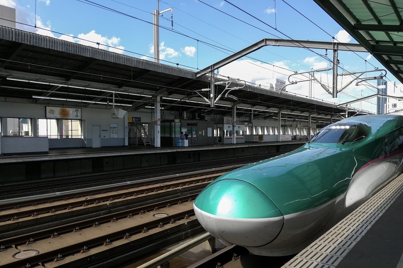 Green Shinkansen train arriving in a station in Japan