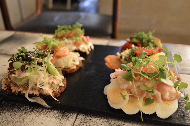 Various smørrebrød on a black platter at Aarhus Central Food Market