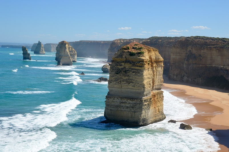 Enormous rocks standing in the ocean and on a beach: the Twelve Apostles in Australia