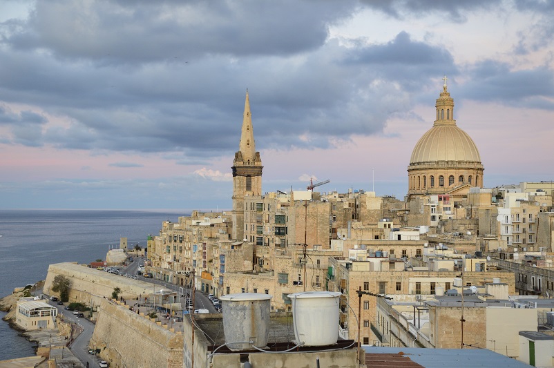 View of rooftops including a large domed church at sunset: one of our favorite Valletta photo spots