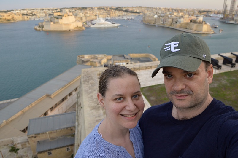 Sarah and Justin in front of a view of the Three Cities from Upper Barrakka Gardens in Valletta