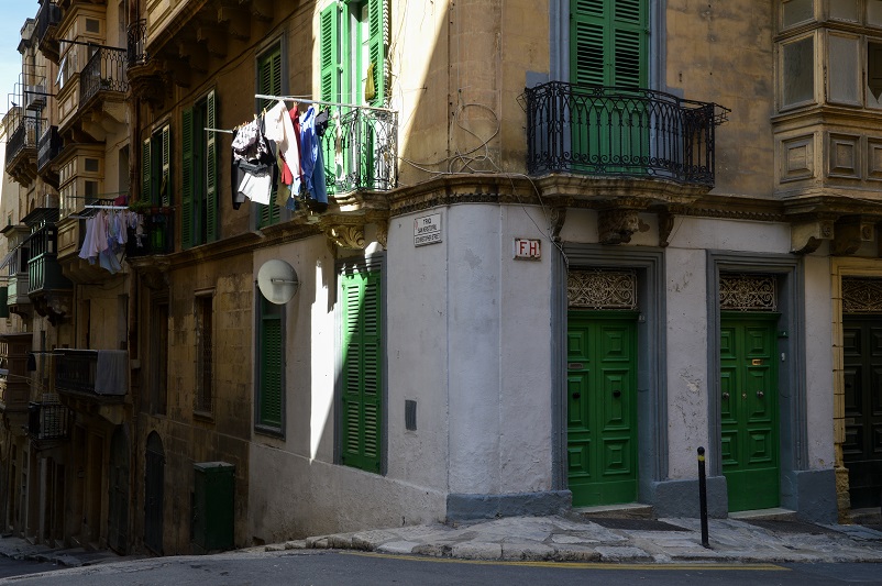 Corner of a street in Valletta with green doors and shutters and laundry