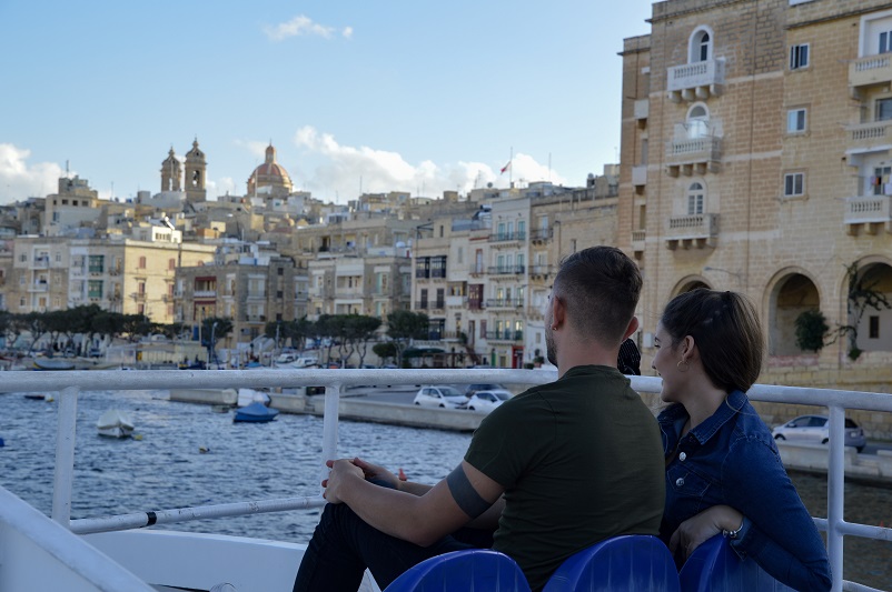 Two people sitting on a boat staring out at the Three Cities in Malta