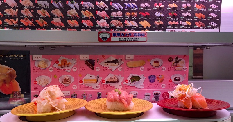 Three plates of sushi in front of signs of sushi: cheap eats in Tokyo