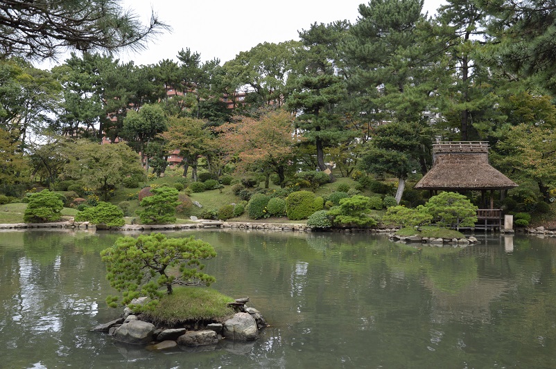 Small island in water surrounded by trees at Shukkei-en Garden in Hiroshima