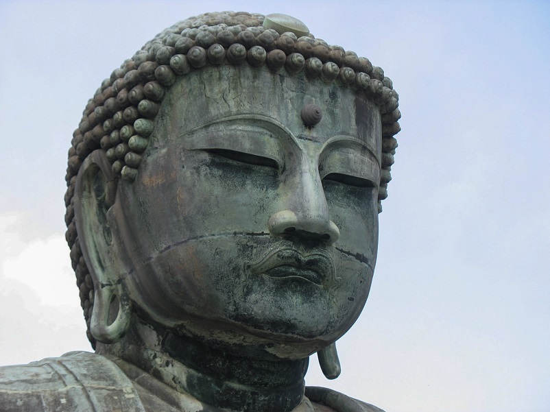 Giant bronze head of Buddha against a blue cloudless sky in Kamakura, Japan
