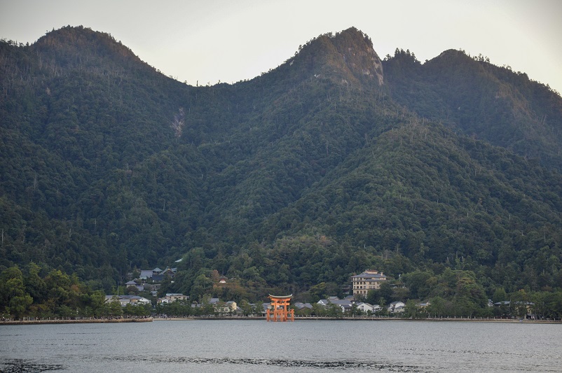 Floating torii gate in front of mountains, taken on the ferry approach to Miyajima