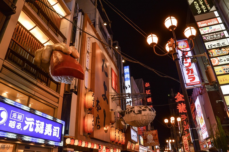 Japanese street signs and a large hand holding a piece of sushi in the Dotonbori area of Osaka