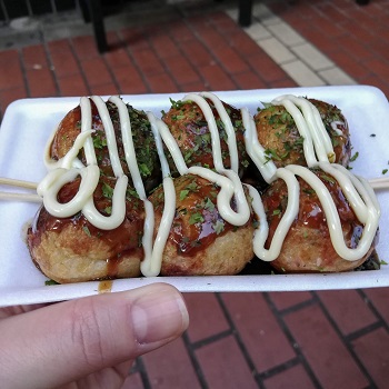 6 takoyaki balls in a container (and Sarah's thumb)