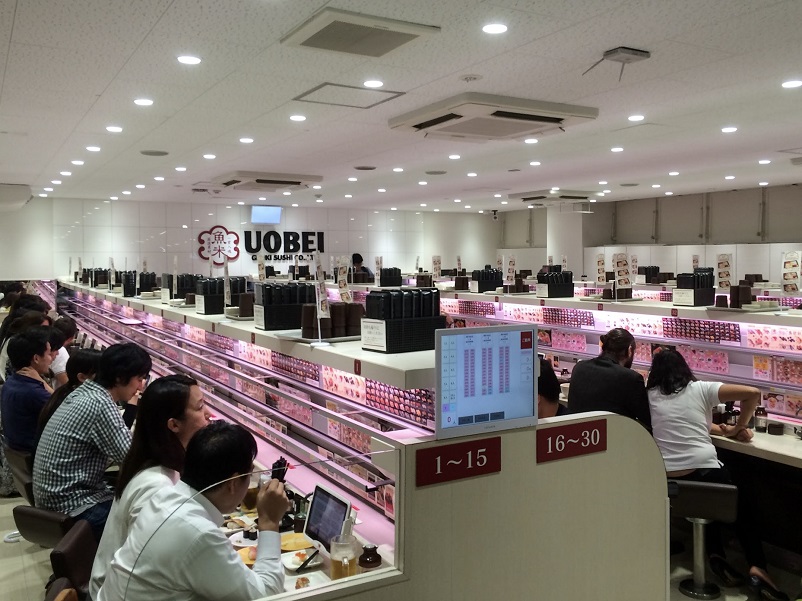 People sitting eating at Uobei, recommended for cheap eats in Tokyo