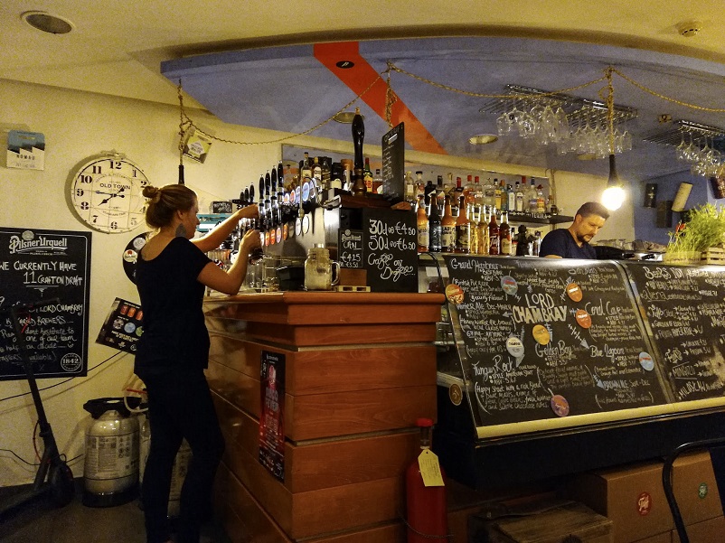 One woman pouring beer and a man behind the bar at 67 Kapitali in Valletta