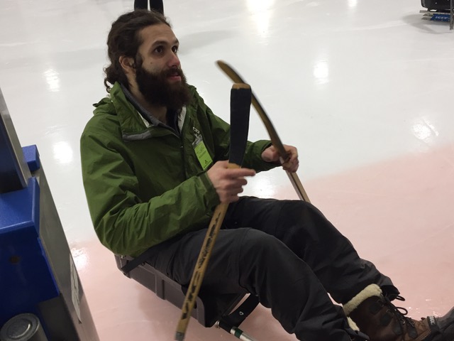 Man in an adapted hockey sled on ice rink